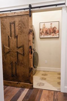 an open wooden door in a room with hard wood flooring and white paint on the walls