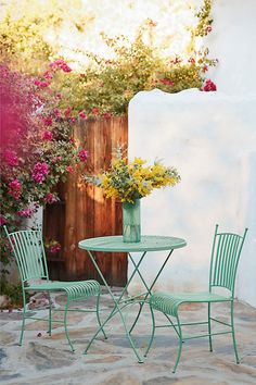 two green chairs and a table with flowers on it