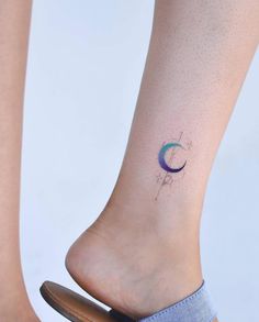 a woman's foot with a small tattoo on her left ankle and the moon behind it