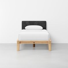 a bed with a black headboard and white sheets on it's back end