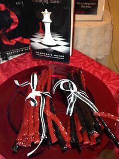 red and black candles are on a plate next to the book, which is also in front of it