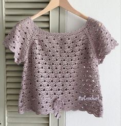 a crocheted top hanging on a wooden hanger