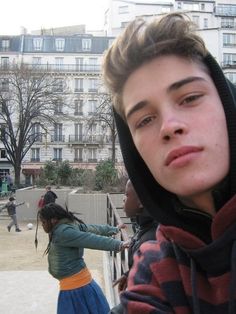 a young man standing next to a woman on top of a sidewalk