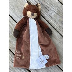 a teddy bear wrapped in a brown and white blanket on top of a wooden floor