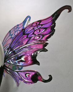 a purple and black butterfly figurine sitting on top of a white table next to a vase