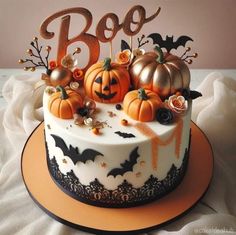 a decorated halloween cake with pumpkins and bats on it's top, sitting on a table