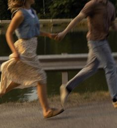 a man and woman are running down the street with their hands in each other's pockets