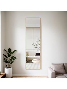 a living room with a couch, mirror and potted plant