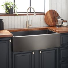 a stainless steel kitchen sink with wooden counter tops and black cabinets in front of a window