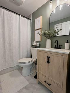 a white toilet sitting next to a sink in a bathroom under a mirror and lights