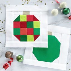 two pieces of quilted fabric with christmas ornaments on the table next to them,