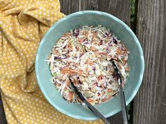 a blue bowl filled with coleslaw slaw next to a yellow polka dot towel