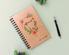 a personalized wooden notebook with flowers on it and a pen next to the cover