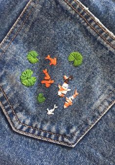 several orange and white fish are in the pocket of a blue jean jacket with green leaves on it