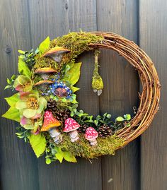 a wreath made out of branches and flowers on a wooden fence with mushrooms, leaves and other plants