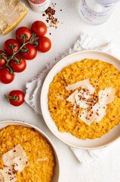 two bowls of riso with tomatoes and cheese on the side next to some bread