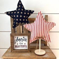 two patriotic stars are sitting on top of a wooden stand next to a sign that says america the beautiful