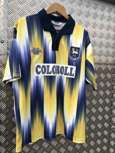 a yellow and blue striped shirt with the word colorado on it hanging from a metal rack