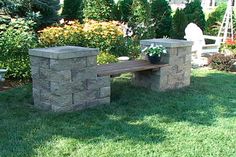 a stone bench sitting on top of a lush green field