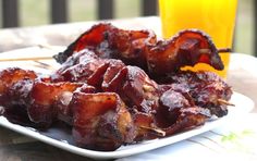 barbecue skewers on a white plate with a glass of orange juice in the background