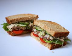 two halves of a sandwich with meat and veggies on it sitting on a white surface