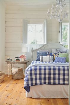 a bedroom with wood floors and white walls, has a blue checkered comforter on the bed