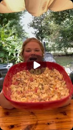 a woman holding a large red bowl filled with food