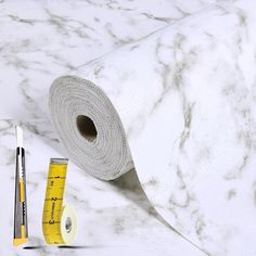 a roll of white marble paper next to a measuring tape