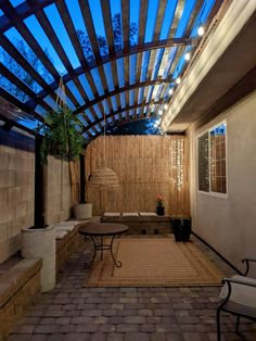 a patio with a table and chairs under a pergolated roof at night time