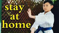 a young boy is practicing karate in front of a fence with the words stay at home