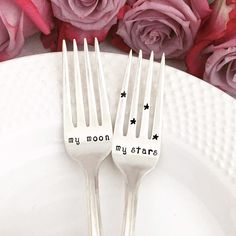 two forks with the words my moon, my star written on them sitting next to pink roses