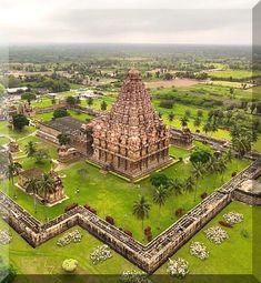 an aerial view of a large temple in the middle of a lush green field with palm trees