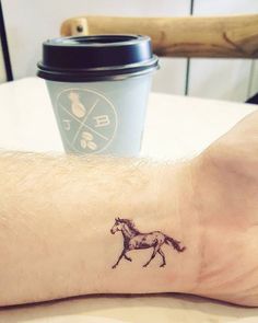 a small horse tattoo on the left ankle and foot, next to a cup of coffee