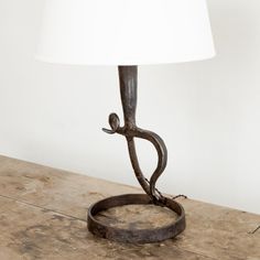 a lamp that is sitting on top of a wooden table with a white shade over it