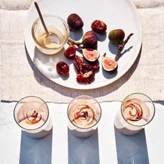 an overhead view of figs and glasses on a table with the top half eaten