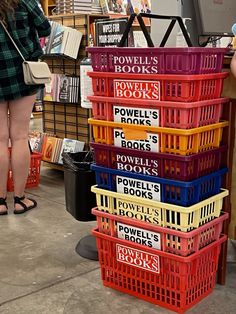 a woman standing next to a stack of books in a room filled with lots of books