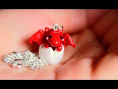 a tiny red and white elephant necklace on someone's hand