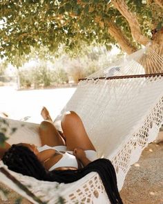 a woman laying in a hammock under a tree