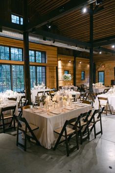 a dining room with tables and chairs covered in white tablecloths set for an event