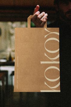 a person holding a brown paper bag with the word 100 on it in front of them