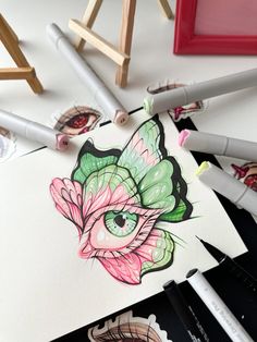 some markers and pencils are laying on top of a paper with an image of a butterfly