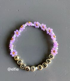 a beaded bracelet with the word baby spelled in gold and pink beads on a gray surface