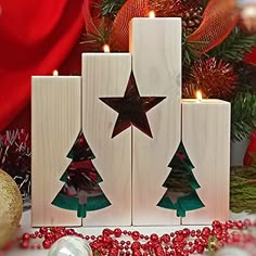 three wooden blocks decorated with christmas trees and stars, surrounded by holiday decorations in front of a red background