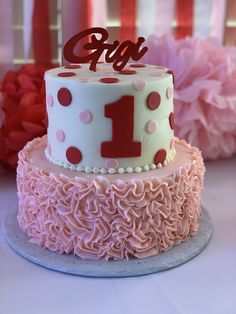 two tiered cake with pink and white icing on top, decorated with polka dots