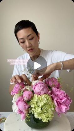 a woman arranging flowers in a vase on a table