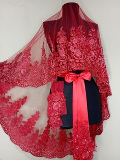 a woman's red dress and shawl on display in front of a white wall