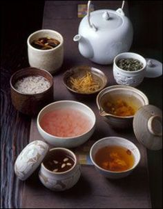 there are many bowls with different types of food in them on the table next to a tea pot