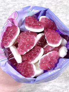 a person holding a purple bag filled with heart shaped candies