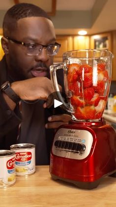 a man is making strawberries in a blender