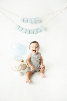 a baby sitting in front of a birthday cake and banner with the words happy birthday on it